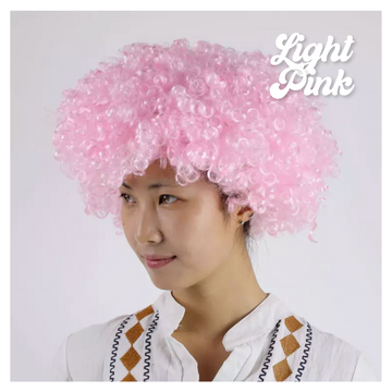 Person wearing a light pink curly wig on a plain background